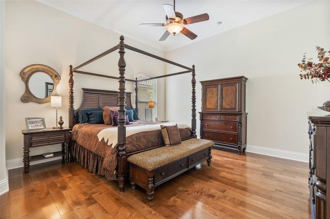 This spacious bedroom exudes warmth with rich hardwood floors, high ceilings, and elegant trim details, offering comfort and flexibility for family or guests. | Image 21