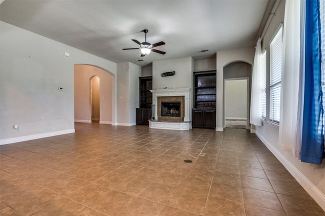 Unfurnished living room featuring arched walkways, a tiled fireplace, a ceiling fan, and tile patterned flooring | Image 7