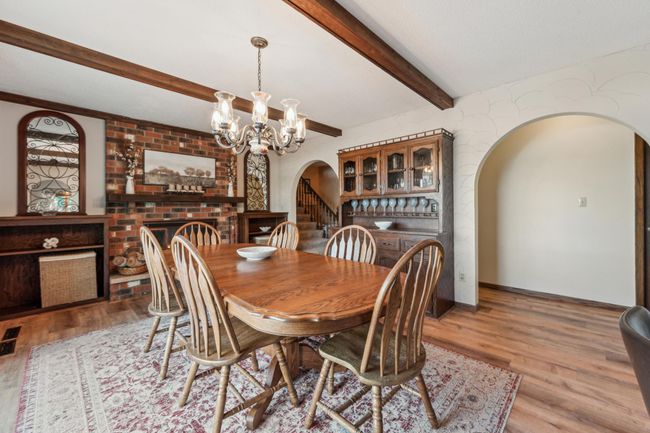 Brick fireplace adds warmth and character to this elegant dining room featuring wood-beamed ceilings and built-in shelving. | Image 10