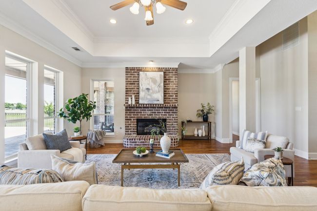 This gorgeous living room is anchored by the gas fireplace. Freshly painted with modern, neutral warmth, the room also boasst wood flooring, a tray ceiling with crown moulding giving extra height and openness, and ceiling fan. | Image 8