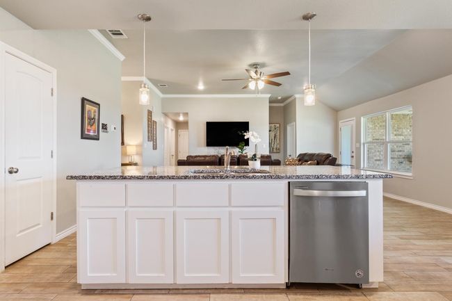 Kitchen with stainless steel dishwasher, open floor plan, stone countertops, light wood-style flooring, and crown molding | Image 16