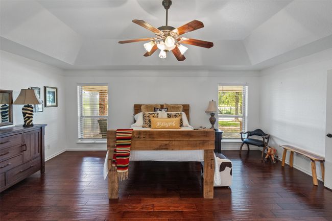 Bedroom featuring a ceiling fan, baseboards, a raised ceiling, and dark wood-style floors | Image 13