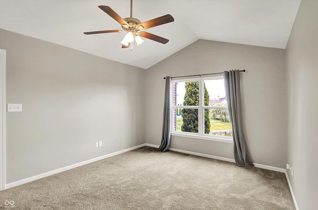 primary bedroom with carpet floors, lofted ceiling, ceiling fan, water view and a massive walk in closet | Image 21