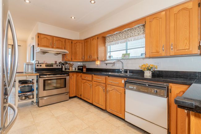 Kitchen featuring stainless steel appliances, under cabinet range hood, a sink, tasteful backsplash, and recessed lighting | Image 15