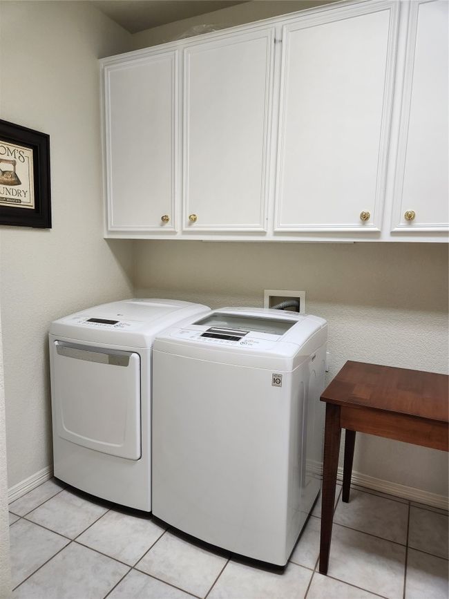 Laundry room featuring cabinet space, washing machine and dryer, and light tile patterned flooring | Image 17