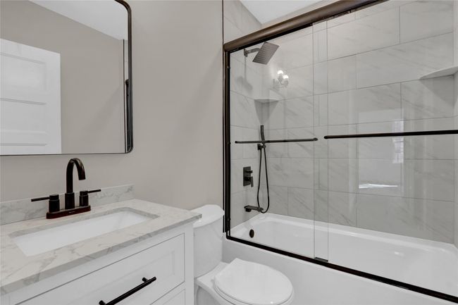 Bathroom featuring combined bath / shower with glass door, vanity, and toilet | Image 16