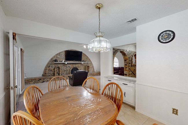 Dining space featuring a wainscoted wall, a chandelier, a textured ceiling, brick wall, and visible vents | Image 9