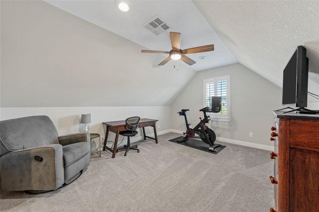 Exercise area with ceiling fan, vaulted ceiling, visible vents, carpet flooring, and baseboards | Image 32