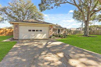 There is a 2-car garage with a long driveway. | Image 2