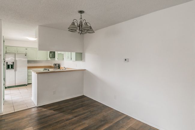 Kitchen featuring white refrigerator with ice dispenser, a peninsula, stainless steel range with electric cooktop, black microwave, and a chandelier | Image 11
