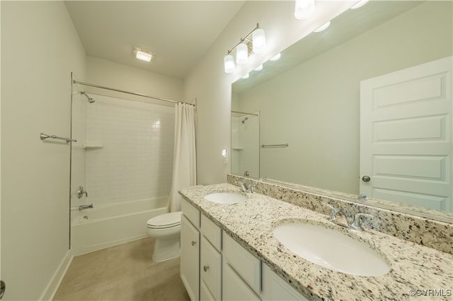 Full bath featuring shower / bathtub combination with curtain, toilet, and double vanity | Image 28