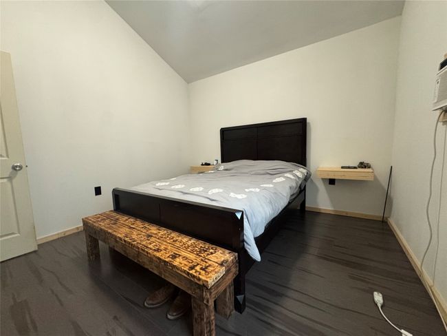 Bedroom with dark wood finished floors and lofted ceiling | Image 10