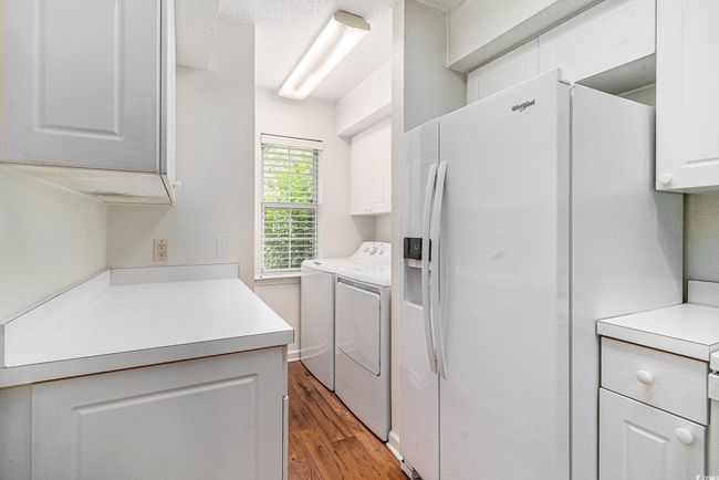 Laundry area with cabinet space, separate washer and dryer, and wood finished floors | Image 13