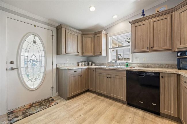 Kitchen featuring light wood-type flooring, dishwasher, crown molding, and a sink | Image 7