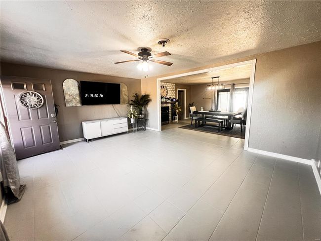Living room with a textured ceiling, visible vents, and baseboards | Image 11