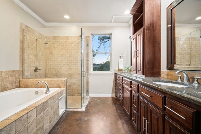 Bathroom with double vanity, a stall shower, ornamental molding, a sink, and a garden tub | Image 30