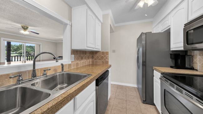 Kitchen featuring ceiling fan, backsplash, sink, light tile patterned flooring, and stainless steel appliances | Image 12