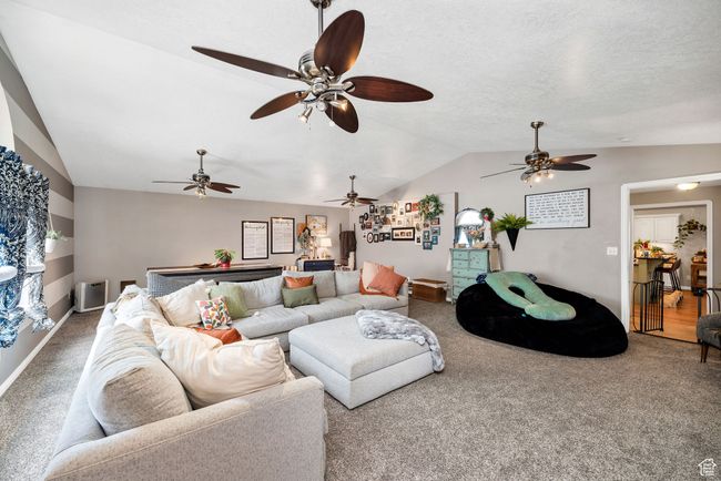 Carpeted living room with ceiling fan, vaulted ceiling, and baseboards | Image 14