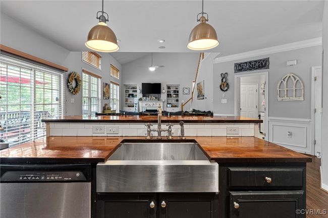 Kitchen with a fireplace, butcher block countertops, stainless steel dishwasher, and dark cabinets | Image 9