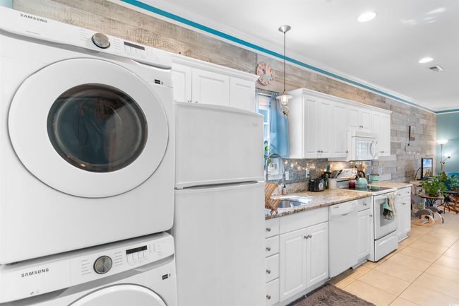 Washroom with stacked washing machine and dryer, light tile patterned floors, and recessed lighting | Image 15