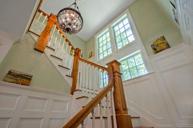 Stairs with a towering ceiling, a chandelier, healthy amount of natural light, and a decorative wall | Image 15