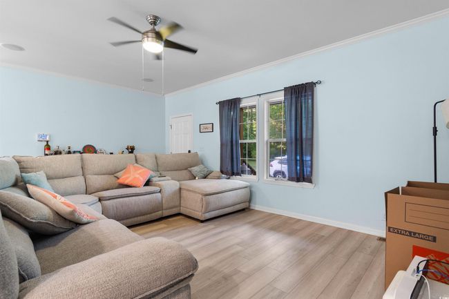 Living area featuring light wood-style floors, ceiling fan, ornamental molding, and baseboards | Image 9