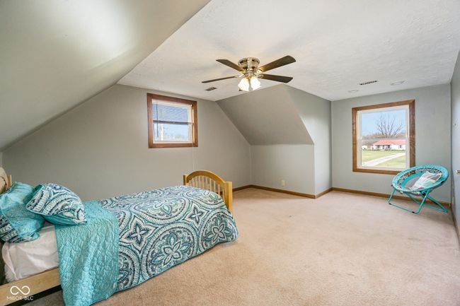 carpeted bedroom with a ceiling fan, baseboards, vaulted ceiling, and a textured ceiling | Image 19