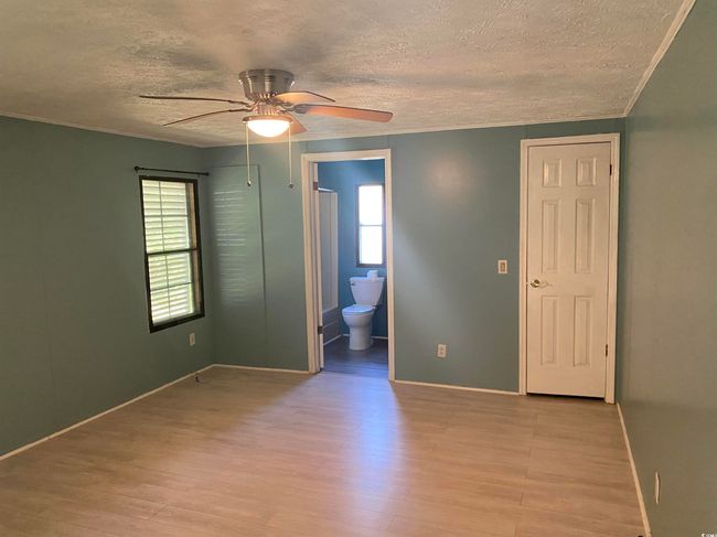 Spare room featuring a textured ceiling, ceiling fan, light wood finished floors, and crown molding | Image 20