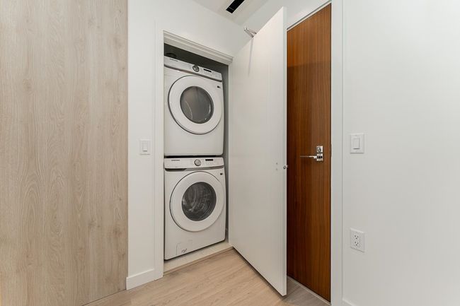 Laundry area with light wood-style floors and stacked washer / drying machine | Image 20