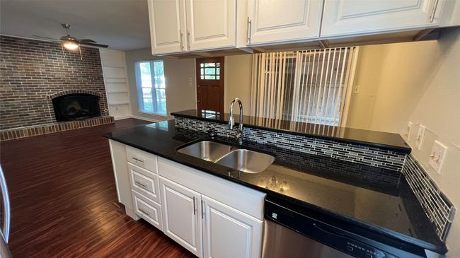 Kitchen with a sink, stainless steel dishwasher, ceiling fan, dark wood-style flooring, and white cabinetry | Image 6