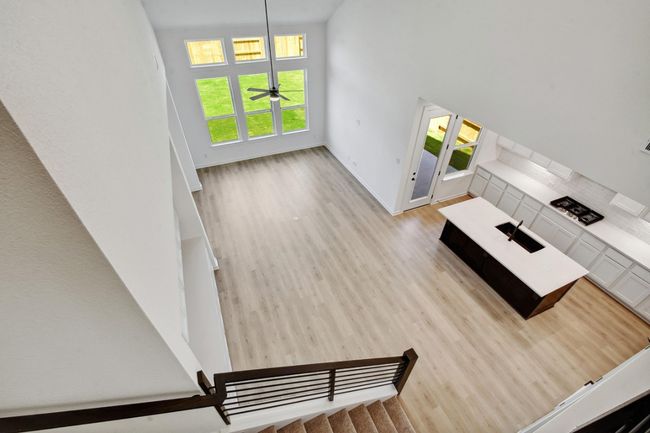 Unfurnished living room featuring light wood-type flooring, a towering ceiling, and a ceiling fan | Image 10
