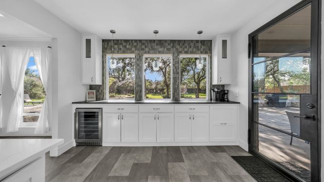 Indoor bar featuring beverage cooler, plenty of natural light, and decorative light fixtures | Image 14