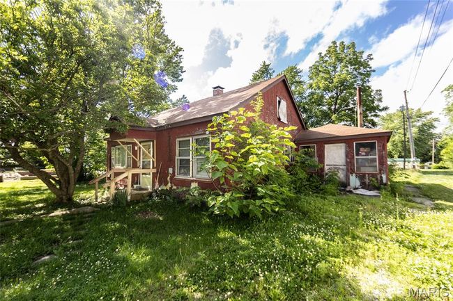 View of side of property featuring a sunroom, a chimney, and a yard | Image 6