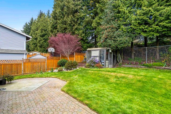 View of yard featuring a patio area, a fenced backyard, an outdoor structure, and a greenhouse | Image 33