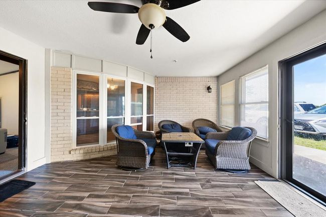 Sunroom featuring a ceiling fan, wood finished floors, and brick wall | Image 35