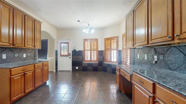 Explore culinary delights in this stunning kitchen, featuring sleek granite countertops, ample cabinetry, and elegant tile flooring. Perfect for both everyday cooking and entertaining. | Image 11