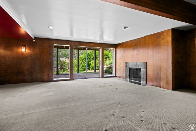 Unfurnished living room featuring wooden walls, carpet, and a fireplace | Image 29