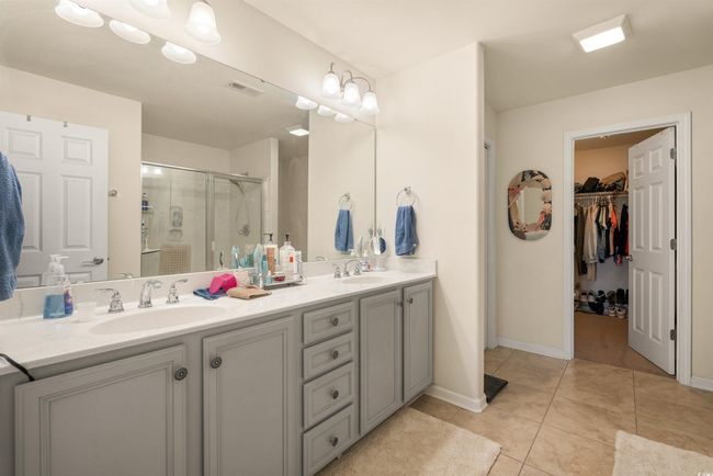 Full bath with a stall shower, double vanity, a spacious closet, tile patterned floors, and baseboards | Image 9