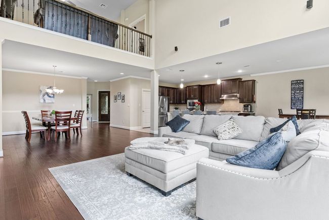 Living room featuring baseboards, a towering ceiling, dark wood-type flooring, recessed lighting, and a chandelier | Image 7