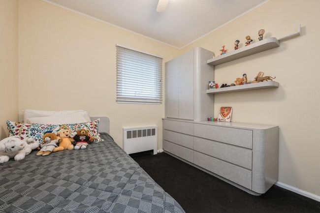 Bedroom featuring radiator, baseboards, dark colored carpet, and ceiling fan | Image 16