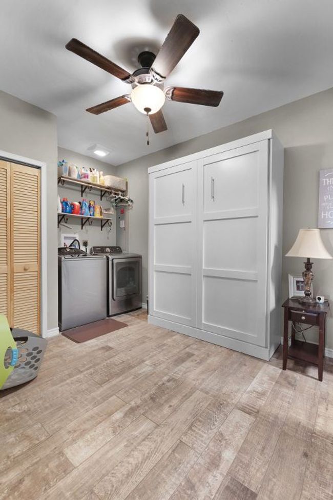 Clothes washing area featuring light wood-style flooring, washer and dryer, baseboards, ceiling fan, and laundry area | Image 21