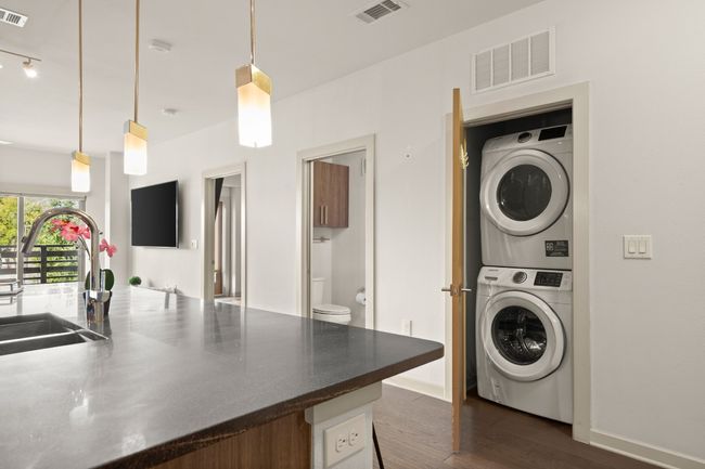 Laundry room featuring estacked washer and dryer, dark wood finished floors, and baseboards | Image 30