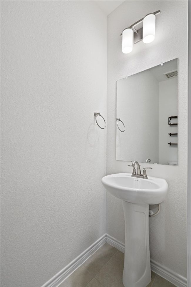 The half bath features a pedestal sink, toilet and tile flooring. | Image 20