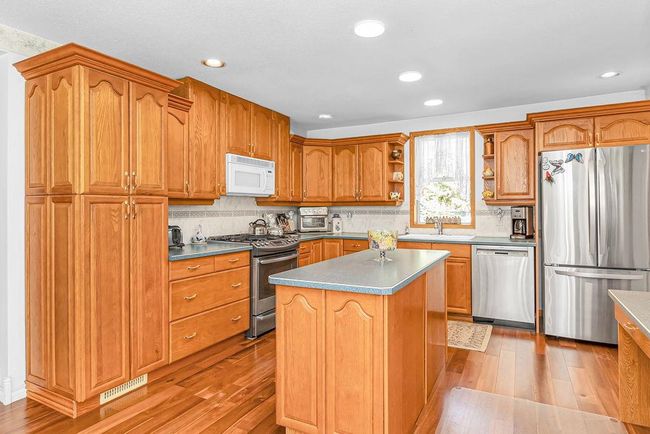 Kitchen with a sink, open shelves, light wood-style flooring, and appliances with stainless steel finishes | Image 6