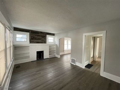 Unfurnished living room featuring a textured ceiling, a wealth of natural light, and dark hardwood / wood-style floors | Image 3