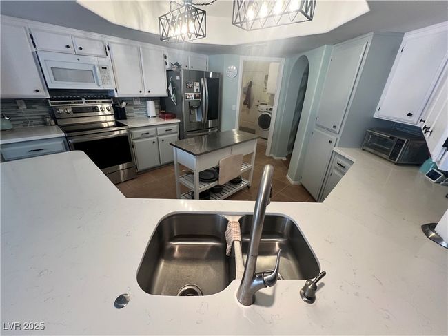 Kitchen featuring appliances with stainless steel finishes, washer / dryer, decorative backsplash, tile patterned flooring, and arched walkways | Image 20