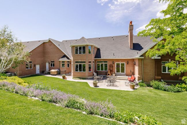 Rear view of property featuring a patio, entry steps, a yard, a chimney, and brick siding | Image 91