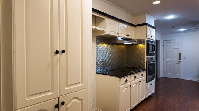 Kitchen featuring stainless steel oven, under cabinet range hood, dark countertops, black electric stovetop, and built in microwave | Image 16