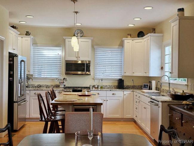 Kitchen with appliances with stainless steel finishes, white cabinetry, hanging light fixtures, and a sink | Image 21