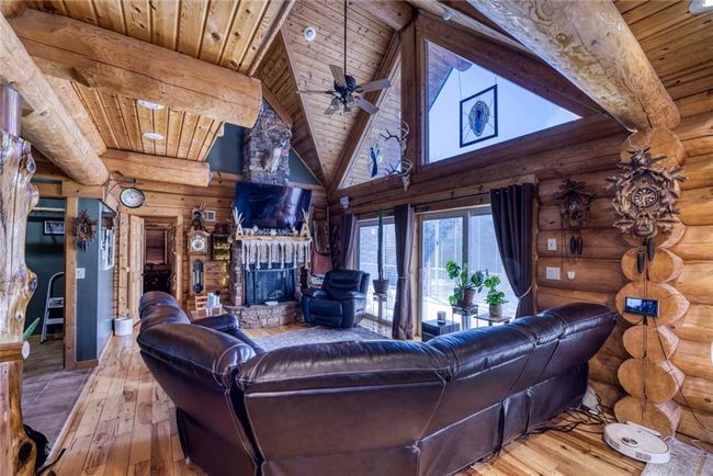 Living area with beamed ceiling, high vaulted ceiling, wood-type flooring, wooden ceiling, and a brick fireplace | Image 14